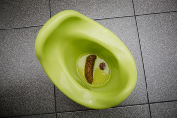 A green children's potty with feces in the toilet