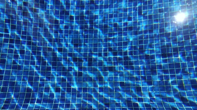 Abstract background, water waves and lines of blue tile in hotel swimming pool with shiny sunlight reflection. Summer and holidays concept.