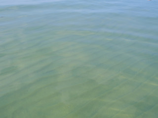 Background. Transparent calm water surface of the lake. Ribbed sand bottom.