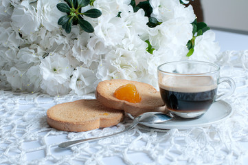 Fototapeta na wymiar Apparecchiatura romantica del tavolo della colazione, con fiori di azalea bianca, tazza di caffè e biscotti con marmellata