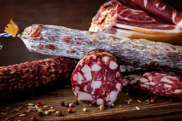 Traditional sausage , sausage with mold and spanish ham( bellota, jamon). Sliced sausage salami on wooden board with spices: pepper and fennel. Close-up.