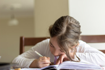 Naklejka premium she is making her homework. The primary school student is making herself homework