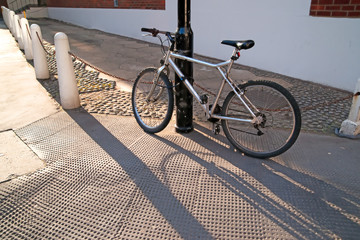 Fototapeta na wymiar Silver bicycle chained to a lamppost.