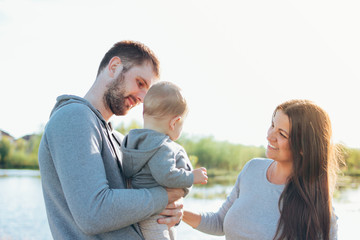 Happy family with Cute baby boy on lake water background outdoors, sensitivity to the nature concept
