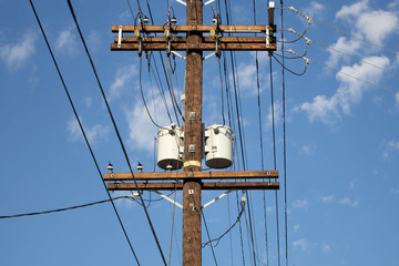 A tall wooden utility pole with electrical wires and transformers 