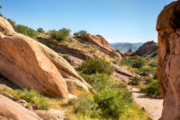Fototapeta na wymiar Red rocky terrain and dry brush at Vasquez Rocks Natural Area Park in Agua Dulce