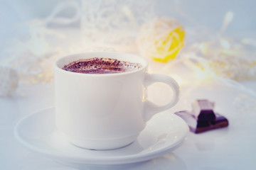 Romantic breakfast. A cup of black coffee with chocolate on a background of glowing lanterns. Postcard Design