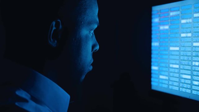 Portrait of african american man programmer coding network security software. Hacker typing code on computer screen in dark office at night