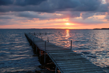 Obraz premium Dramatic summer sunset over lake. Scenic landscape with wooden pier on the lake during beautiful sunset. Lake Mendota, Madison, Wisconsin, USA. 