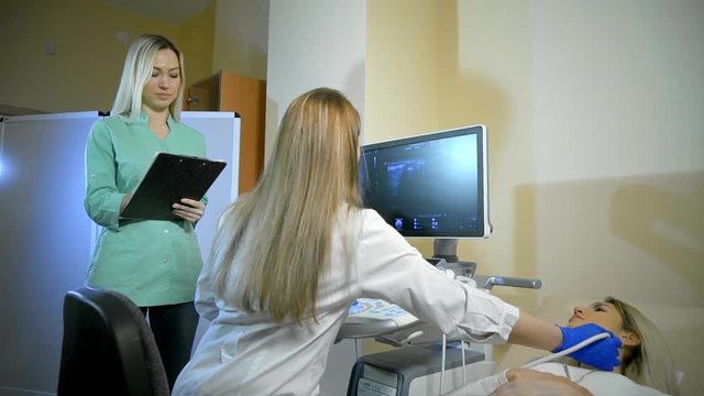 Doctor Taking A Sonogram Thyroid gland, nurse writes and helps the doctor
