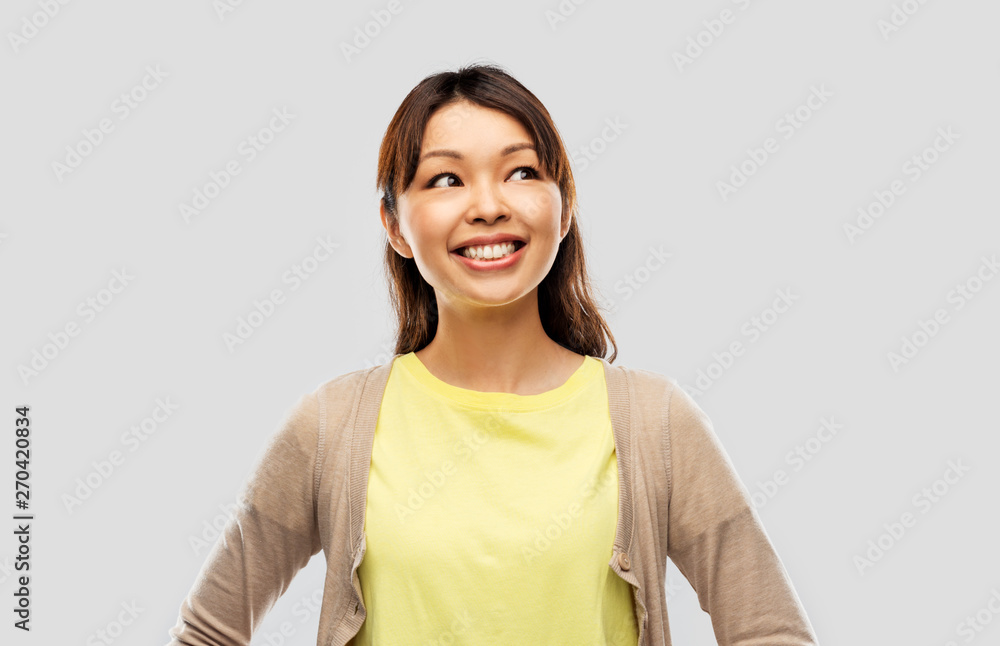 Wall mural people, ethnicity and portrait concept - happy asian young woman looking up over grey background