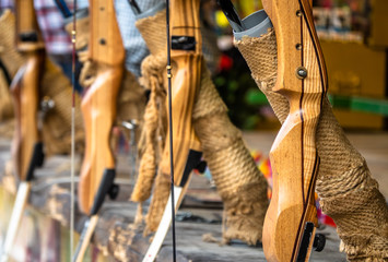 Wooden bows set up in a row at a shooting gallery at the fair, with a shallow depth of focus, weapon