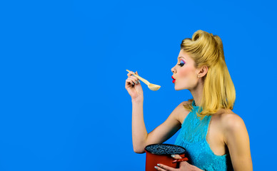 Retro woman cooking in kitchen. Pretty girl in vintage style. Pin up housewife tasting soup with pot by wooden spoon in kitchen. Healthy food. Dieting. Healthy lifestyle. Cooking at home. Prepare food
