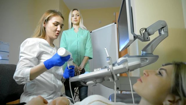 Doctor Taking A Sonogram Thyroid gland, nurse writes and helps the doctor