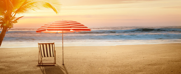 Tropical beach in sunset with beach chair and umbrella