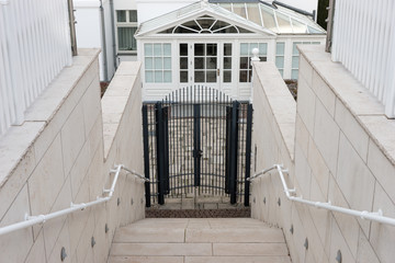 Stairs down to a closed iron gate in front of the entrance hall