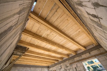 Obraz premium Close-up detail of house room interior under construction and renovation. Energy saving walls of hollow foam insulation blocks, wooden ceiling beams for roof frame.