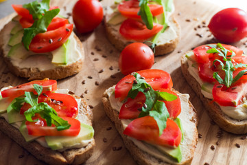 Fresh  toasts with avocado and tomatoes on wooden table 