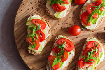 Fresh  toasts with avocado and tomatoes on wooden table 