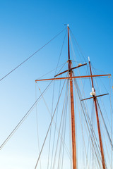 Mast on a yacht with a lot of ropes against a sunny blue sky on a summer day. Bottom view