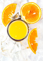 top view of glass of orange juice in ice with orange slices 