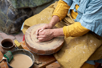 Closeup of an artisan hand making a jug of clay on a craft circle.
