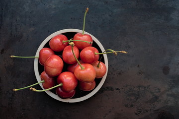 Fresh ripe cherries on a plate on a dark background. Top view, copy space