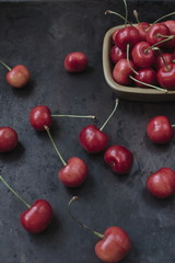 Fresh ripe cherries on a plate and on a dark background. Rustic style.