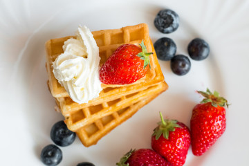  Belgian waffles with Strawberry and Blueberries on white blate close up