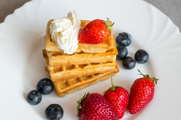  Belgian waffles with Strawberry and Blueberries on white blate close up