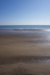 Looking out to sea across empty sandy beach in Scarborough, Yorkshire, UK on a bright bllue sky sunny day