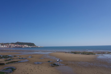 View along beachfront towards castle and harbour in Scarborough, Yorkshire, UK on a clear bright sunny blue sky day