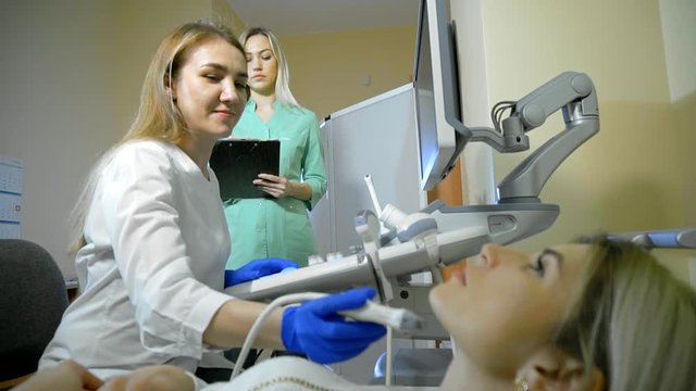 Doctor Taking A Sonogram Thyroid gland, nurse writes and helps the doctor