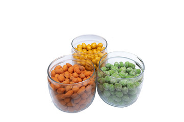Multicolored peanuts in a crispy crust in three glass jars. Isolate on white background