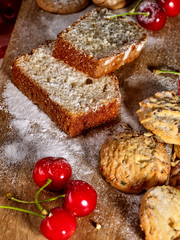 Baking homemade cake. Oatmeal cookies with husk oats and cherry cupcake with powdered sugar on kitchen cutting board gingham checkered cotton fabric on table in village style for picnic.