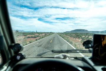 View of the dashboard of a car and the infinite road in the desert