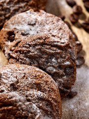 Oatmeal chocolate cookies with coffee grains and cherry, powdered sugar on kitchen cutting board with checkered fabric in village style for picnic. Perfect for breakfast.