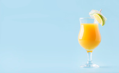 Orange summer alcoholic cocktail with mango juice, rum, liqueur, lime and ice, blue background, copy space