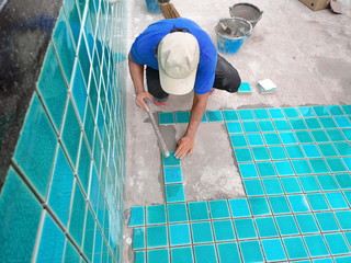 Tiled pool. The man hand while using spacer for installing tiles. construction work.Construction...