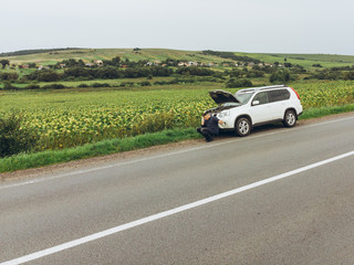 man sitting on road near broken car. trying stop car for help