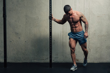 Young strong man posing and flexing his quadriceps legs muscles