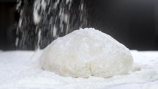 professional Baker sprinkles white wheat flour on top of a ball of raw dough. Traditional bread Making in the kitchen. Close-up, slow