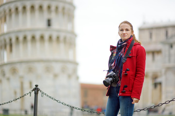 Young female tourist taking photos of the famous Leaning Tower of Pisa.