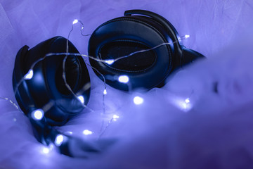 Headphones laying on purple tulle and led lights around them