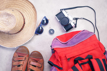 Backpack and compass and sunglasses and camara and hat and leather shoes spread layout on gray background , travel concept.