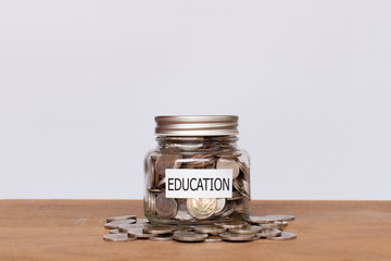 Money coins in glass jar with white background. Education or savings concept