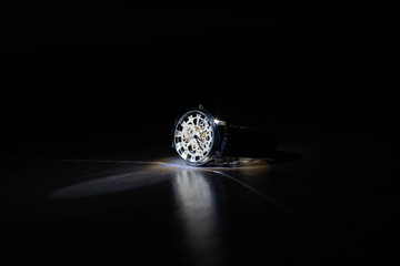 Wrist watch in the dark under light.