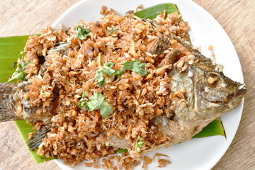 batter fried mango fish topping chop garlic on banana leaf