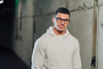 Obraz premium Young strong man in glasses in gym in white hoodie