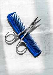 scissors and a blue comb are lying on the white cracked windowsill